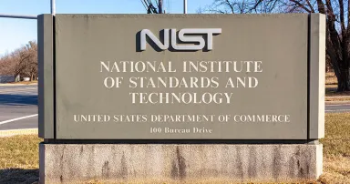 A sign for the National Institute of Standards and Technology is seen in the sunlight at an intersection.
