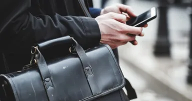 individual holding a briefcase while using a smartphone