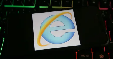 Closeup of mobile phone screen with logo lettering of microsoft internet explorer browser on computer keyboard