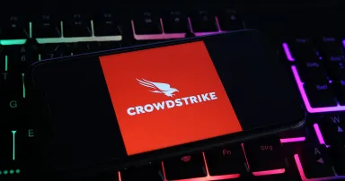 Closeup of mobile phone screen with logo lettering of crowdstrike cyber security company on computer keyboard