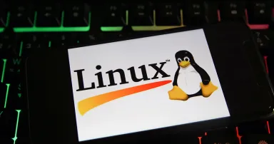 Closeup of a mobile phone screen with logo lettering of linux on computer keyboard