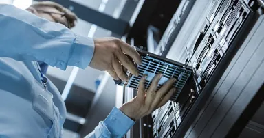 Low Angle Shot In Fully Working Data Center IT Engineer Installs Hard Drive into Server Rack. Detailed and Technically Accurate Footage.