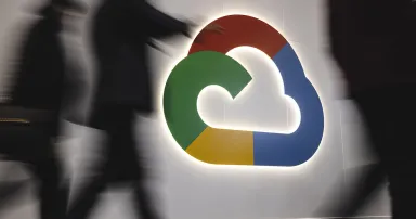 People walk past a Google Cloud logo