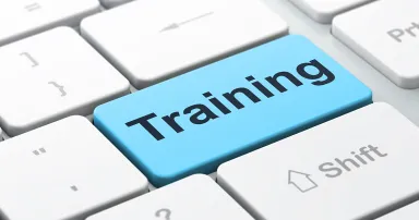 The word "Training" is seen on a blue button on a white computer keyboard