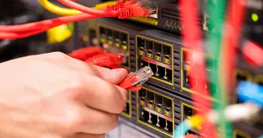 IT technician or engineer connects a gigabit network cable into switch in datacenter