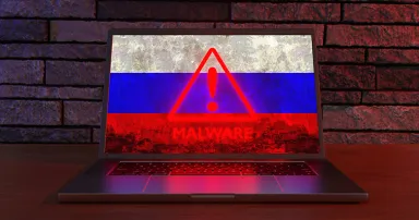 Laptop showing the national flag of Russia and a warning sign of malware. Illustration of the concept of cyber threats, DDOS and hacking activities related to Russia