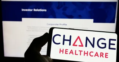 Person holding mobile phone with logo of American company Change Healthcare Inc. on screen in front of business web page.