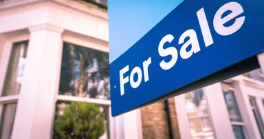Estate agent 'For Sale' sign on street of houses