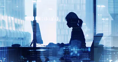 Silhouette of Woman Working in Modern Office A silhouette of a woman working on a computer in a modern office setting