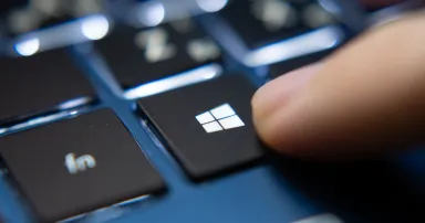 Laptop user pressing Windows Key on Microsoft Windows keyboard.