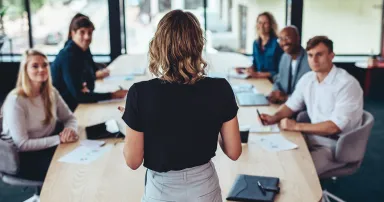 Female manager having a meeting with her team in office boardroom.