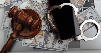 Smartphone with handcuff on a dollar banknotes and judge gavel. Cyber crime and law concept.