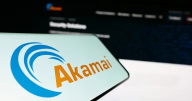 Cellphone with logo of American company Akamai Technologies Inc. on screen in front of business website.