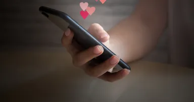 Woman hand holding mobile phone with glowing screen with different virtual hearts