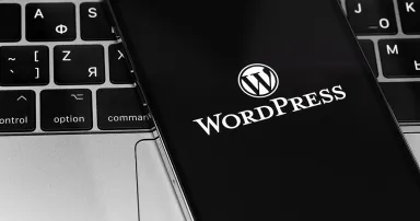 WordPress app logo on the screen smartphone with notebook closeup. WordPress - open source site content management system.