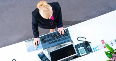 Hotel receptionist working on computer at front desk office