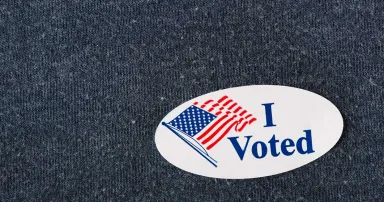 Closeup of an American "I voted" sticker placed on a navy shirt.