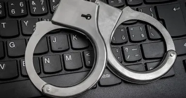 Top view of black keyboard and handcuffs - cyber crime concept