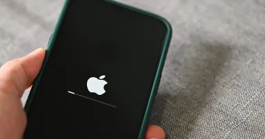 iPhone 13 Pro with apple logo loading and installing operating system ios 15.5 on the screen close up, new ios 2022 on apple devices sub v. ios 15 for updates