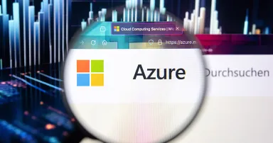 Microsoft Azure company logo on a website with blurry stock market developments in the background, seen on a computer screen through a magnifying glass.