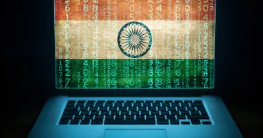 Indian hacker and computer expert. Laptop with binary computer code and India flag on the screen.