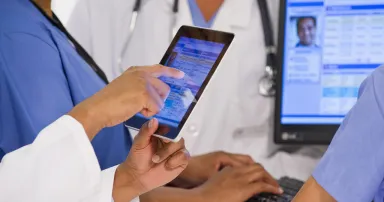 Doctors using digital tablet together in hospital